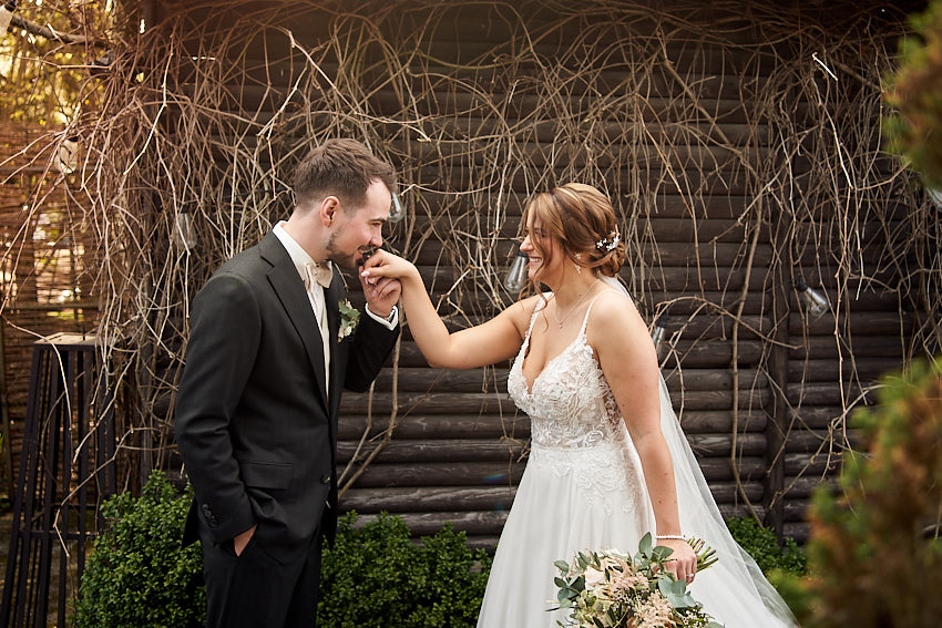 Bräutigam gibt seiner Frau einen Handkuss zur Goldenen Stunde bei den formalen Hochzeitsfotos